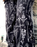 Close up of dark black pants with a print of vintage swords and flowers on loungewear bottoms.